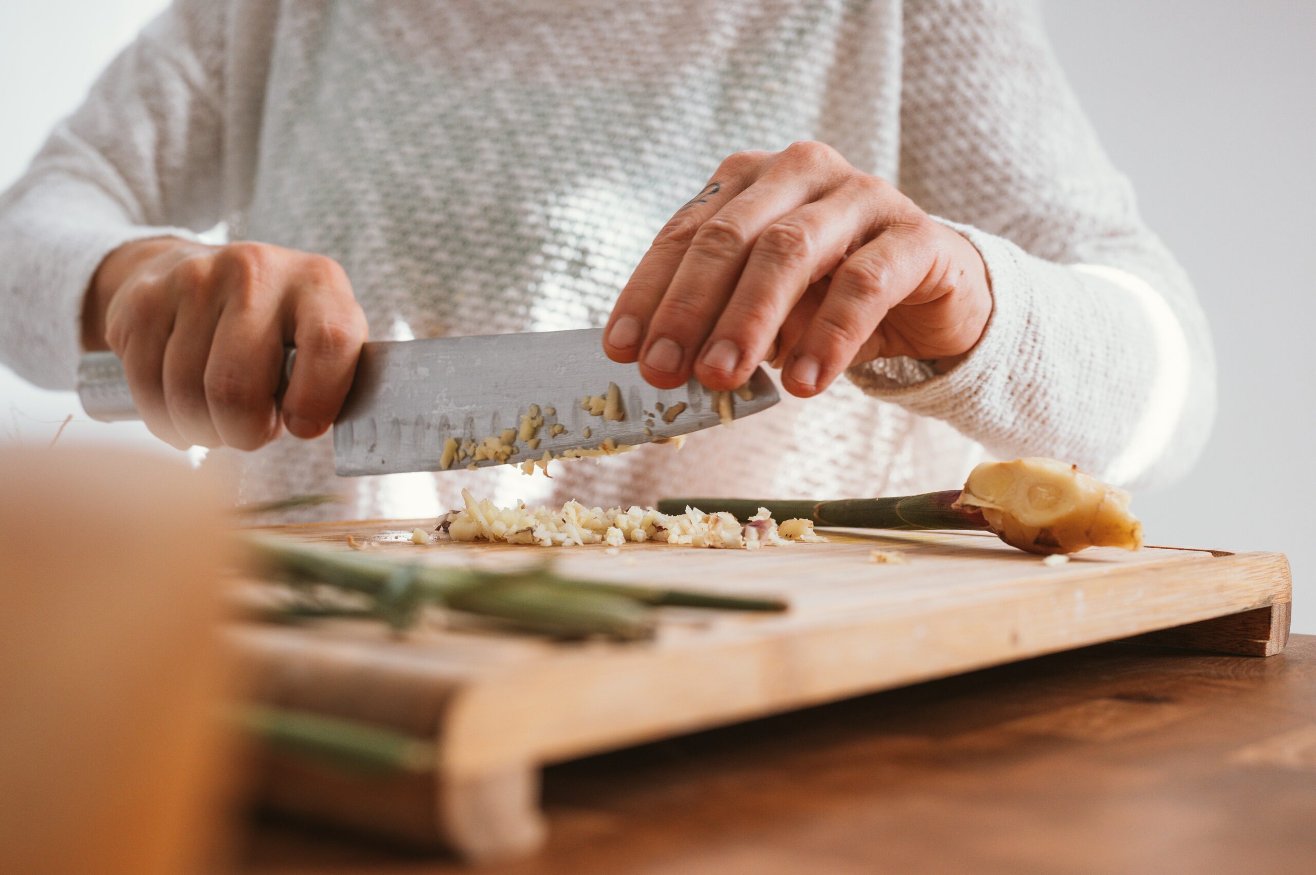 A person chopping vegetables on a wooden table.