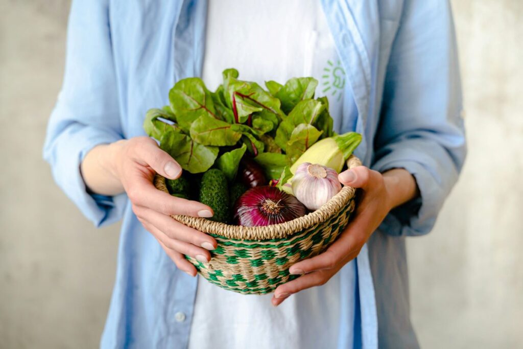 A woman holding a basket full of vegetables.