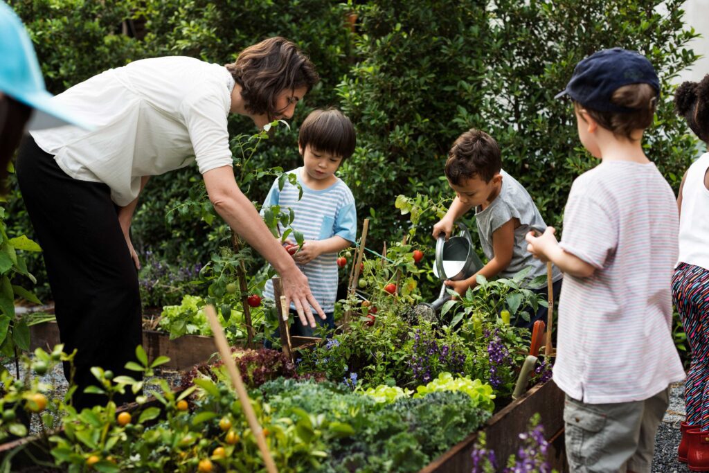 A woman and three children tendering a vegetable garden.