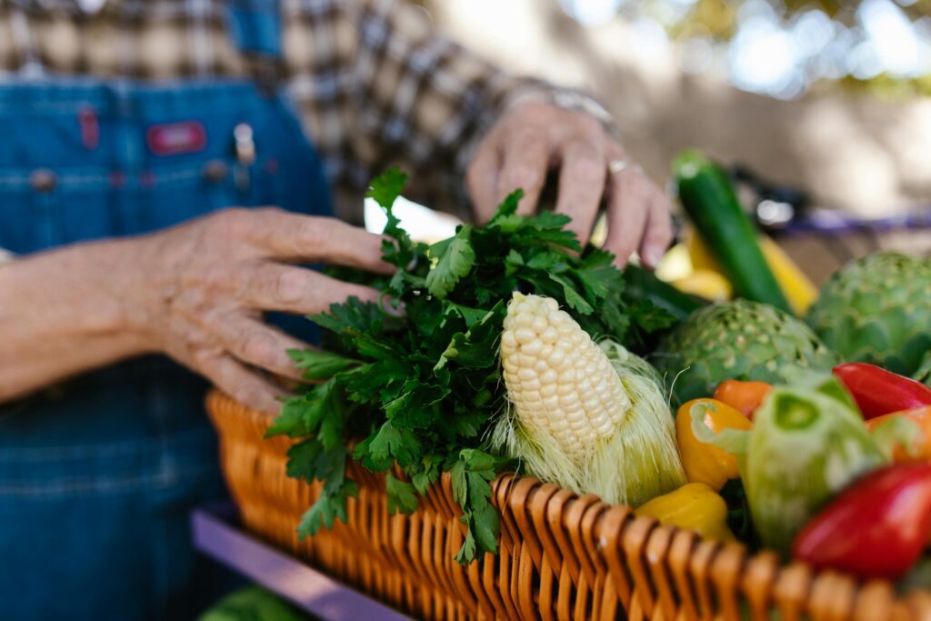 A man holding a wicker basket full of vegetables.